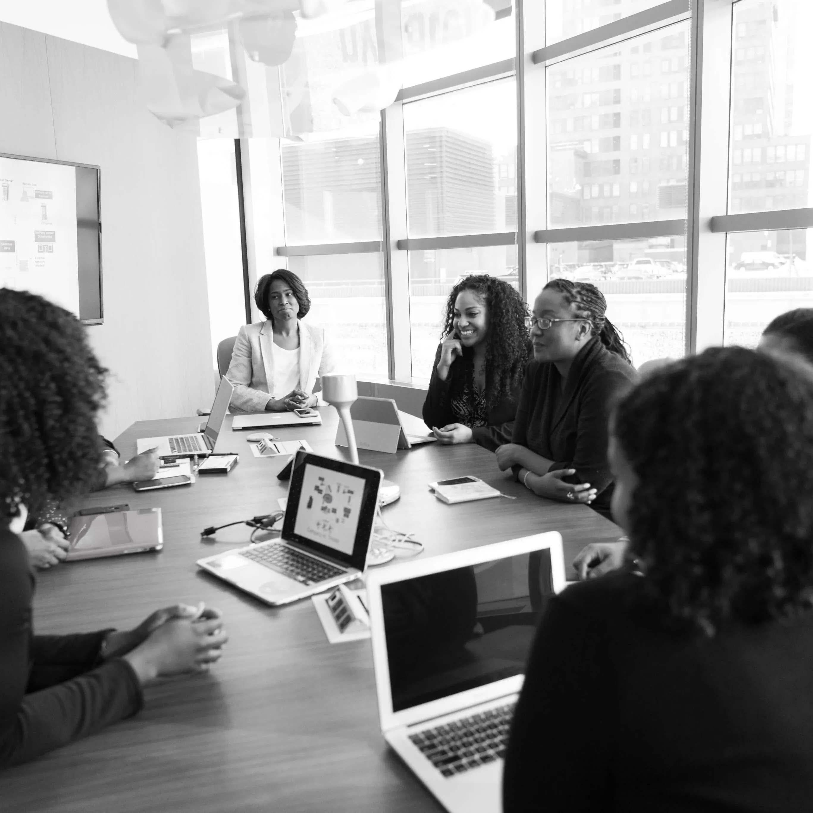 An image of colleagues sitting around a table and working on their computers.
